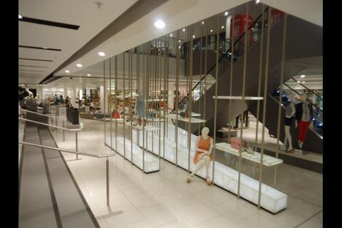 Mannequins lounge on display blocks, peering out from a semi-forest of galvanised metal poles